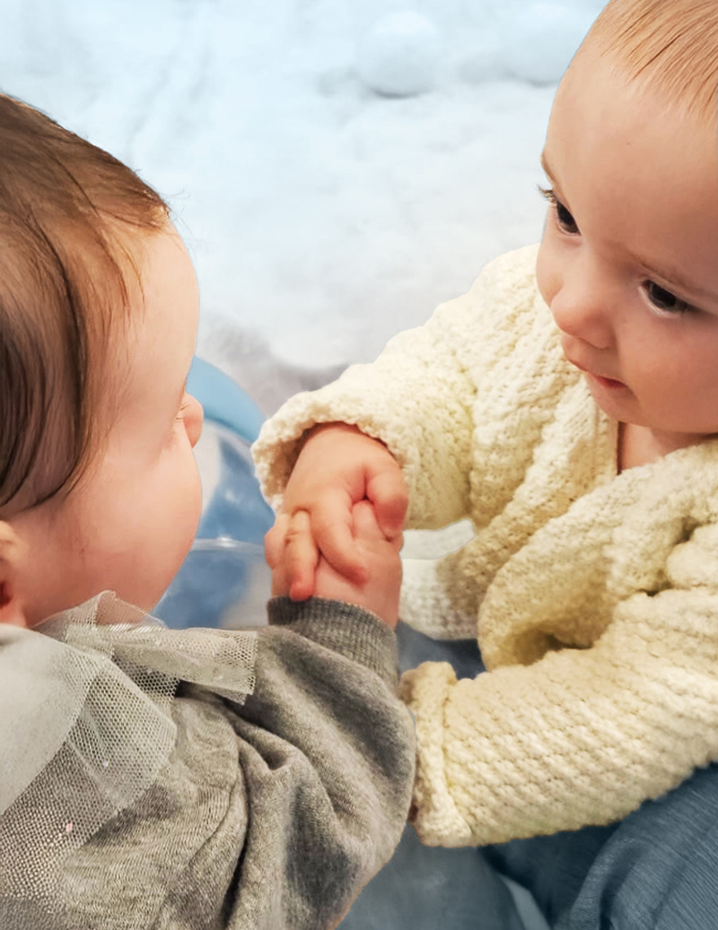 A couple of pre-mobile babies holding hands.